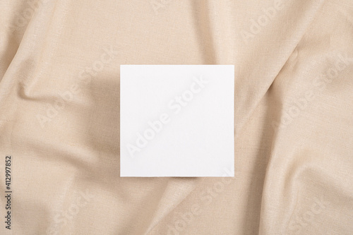 White square invitation card mockup on beige textile background
