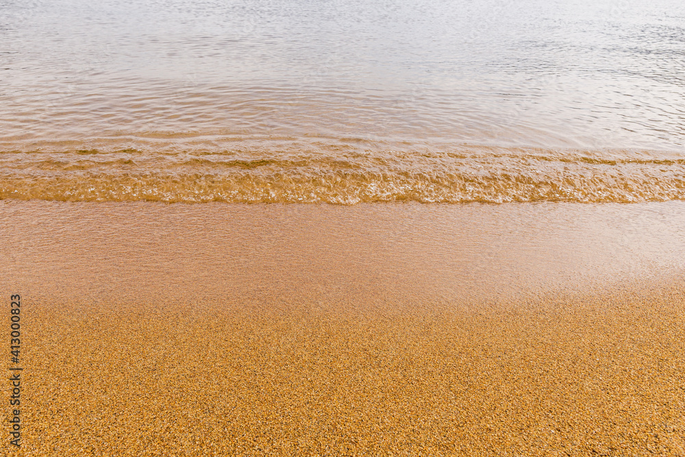 Close-up of a water edge and yellow sand summer beach background with copy space. Close-up of a water edge and yellow sand summer beach background with copy space.