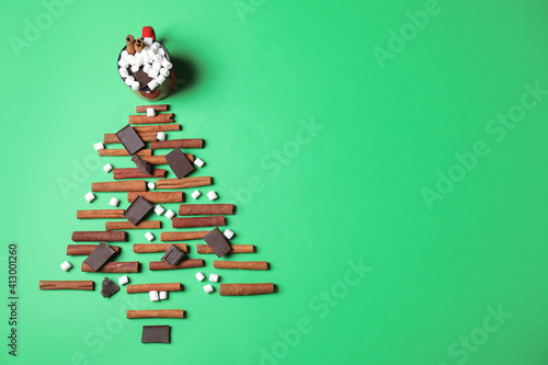 Christmas tree made with marshmallows, cinnamon and chocolate on green background, flat lay. Space for text