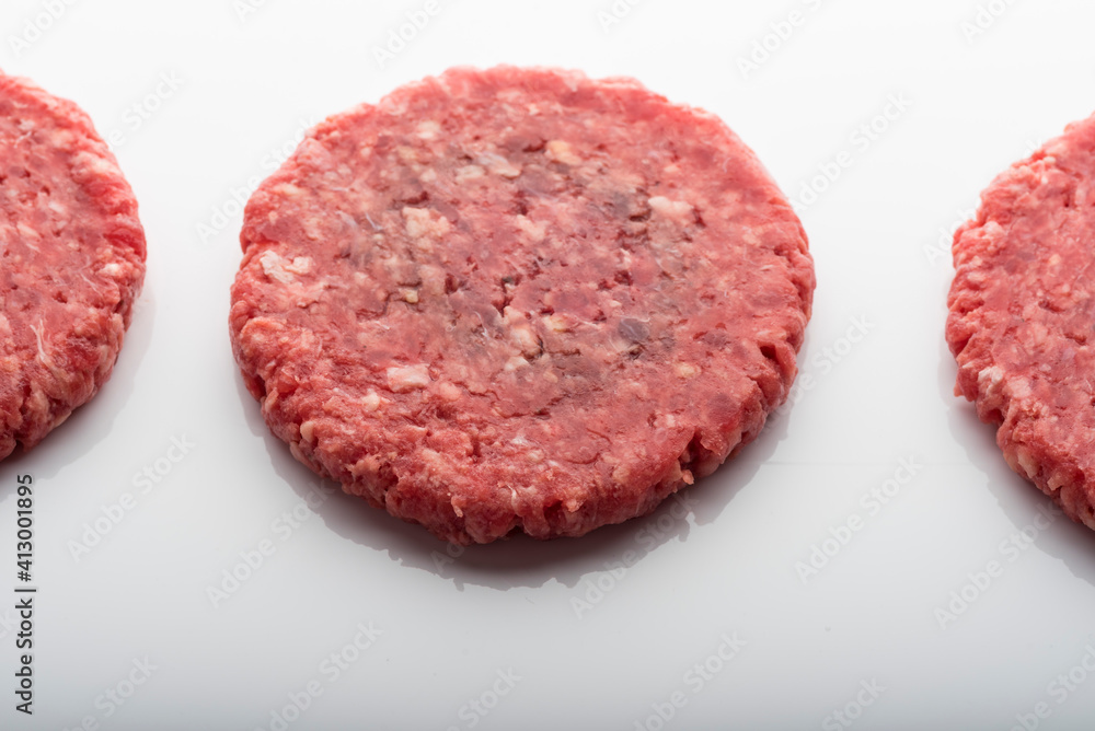 Closeup shot of fresh raw burger patties on a white surface Closeup shot of fresh raw burger patties on a white surface