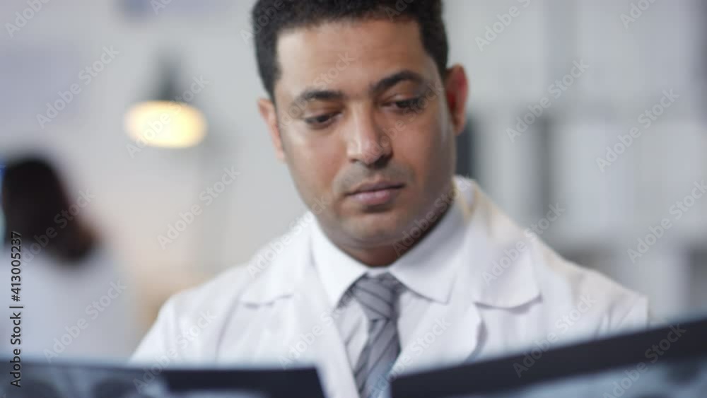 Medium close-up portrait of modern Middle Eastern male doctor working with patients X-ray shots Medium close-up portrait of modern Middle Eastern male doctor working with patients X-ray shots