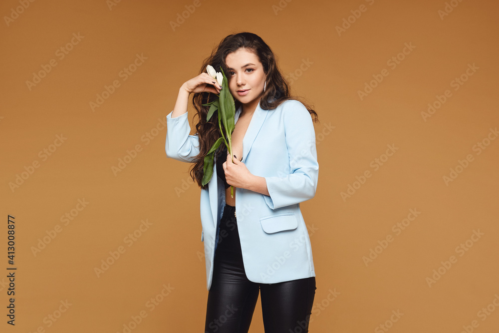 Young woman with perfect slim body posing with tulip flowers over the beige background, isolated with copy space for text and advertisement Young woman with perfect slim body posing with tulip flowers over the beige background, isolated with copy space for text and advertisement