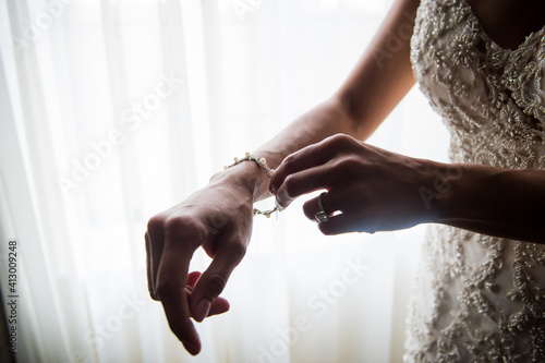 Close up of a bride's hands putting on a diamond bracelet