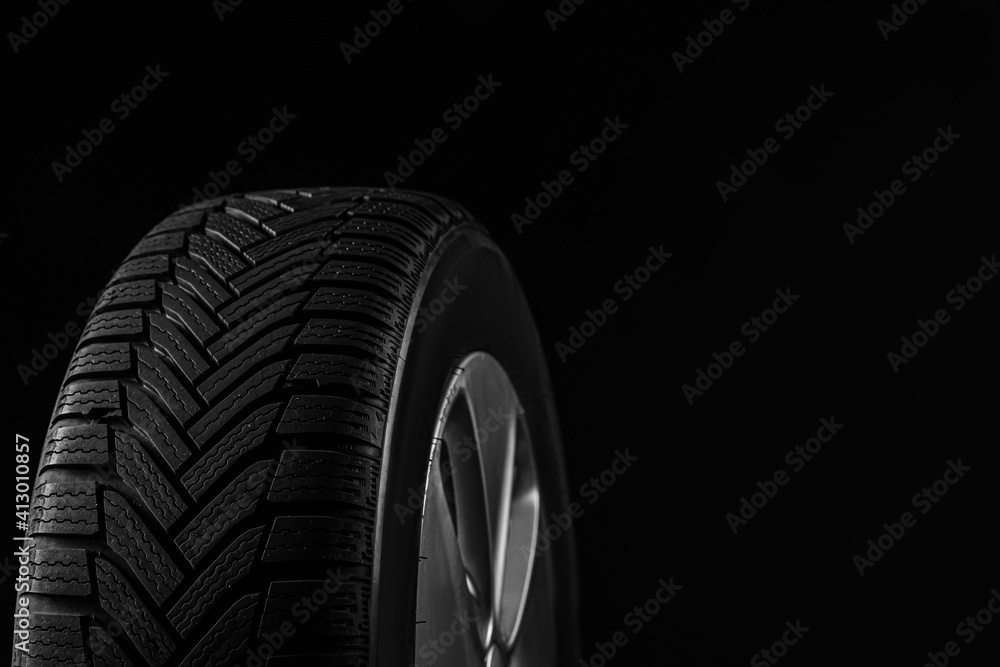 Wheel with winter tire on black background, closeup. Space for text
