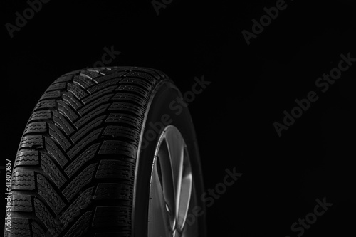 Wheel with winter tire on black background, closeup. Space for text