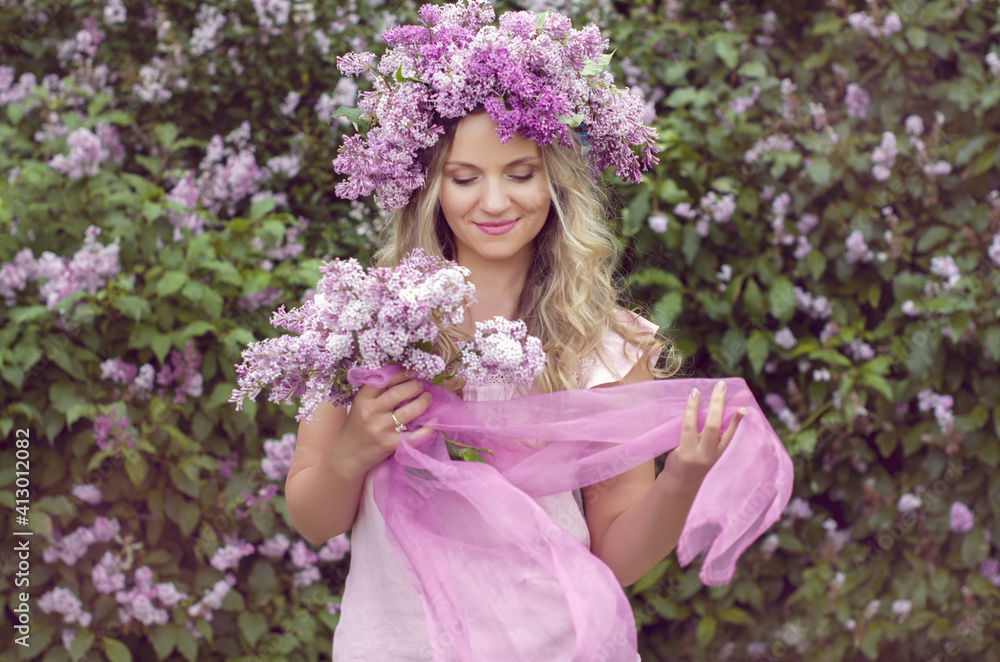 Blonde woman enjoying in a spring garden with blooming lilacs with bouquet, lilac flowers hair style. Spring Concept, Spring blossom, Positive human emotions and feelings. Blonde woman enjoying in a spring garden with blooming lilacs with bouquet, lilac flowers hair style. Spring Concept, Spring blossom, Positive human emotions and feelings.