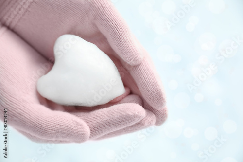 Woman holding heart shaped snowball in hands, closeup