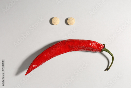 Sad face made of chili pepper and pills on light grey background, flat lay. Potency problem