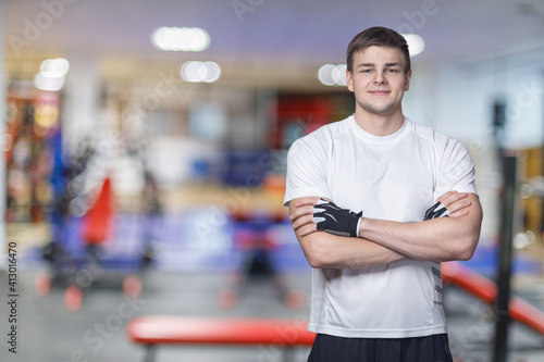 Young man athlete stands in fitness gloves .