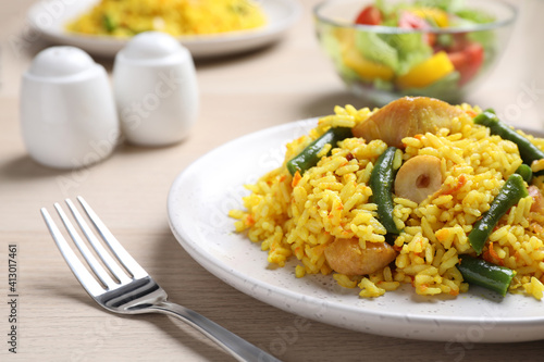 Delicious pilaf with chicken meat on wooden table