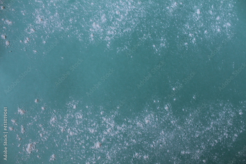 Obraz premium Background meal flour or powdered sugar scattered on a mint blue green background with a copypeist eat for text