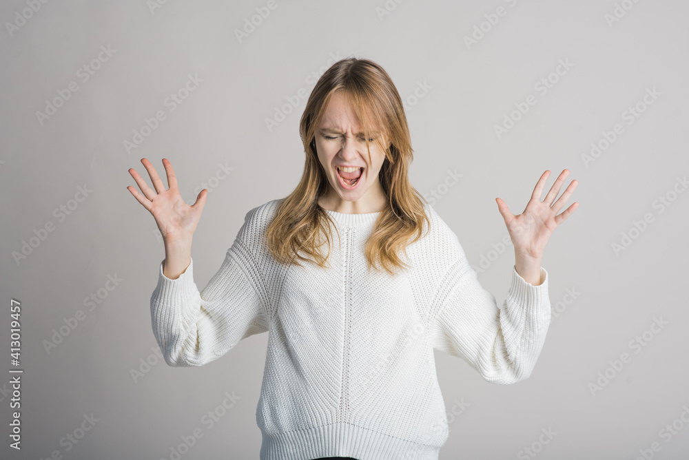 Portrait of a beautiful girl on a white background in the studio who is angry and screams Portrait of a beautiful girl on a white background in the studio who is angry and screams