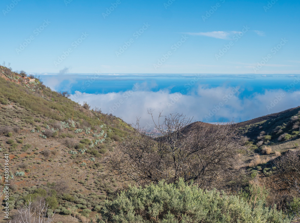 View of Gran Canaria landscape from a hill with clouds and Atlantic ocean in the background. Canary island, Spain