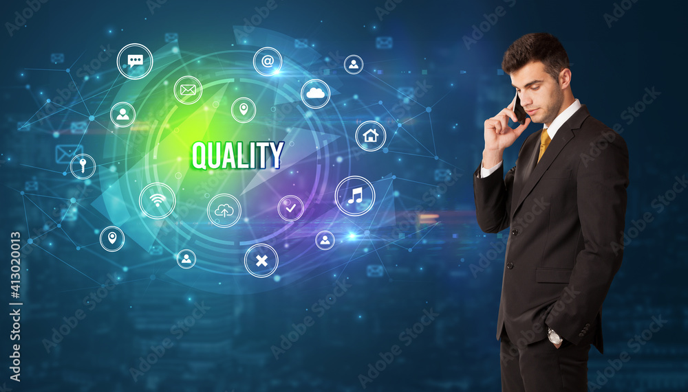 Businessman thinking in front of technology related icons and QUALITY inscription, modern technology concept Businessman thinking in front of technology related icons and QUALITY inscription, modern technology concept