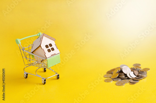 there is a small house in a grocery cart on the yellow table. money accumulation concept © Nastya