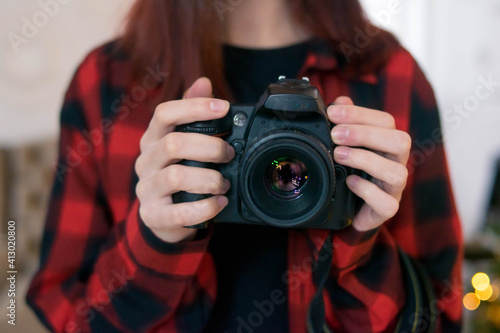 The camera is in the hands of the girl. Christmas..Checkered shirt. Red. Technics. Photographer. PHOTOSESSION.