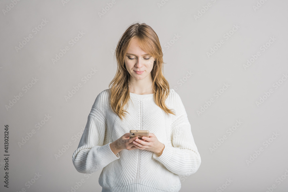 Portrait of a beautiful girl on a white background in the studio who uses a smartphone Portrait of a beautiful girl on a white background in the studio who uses a smartphone