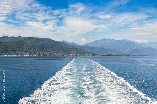 Sea and kielwater seen from ship trail on the water. View of Tivat coastline from ship photo