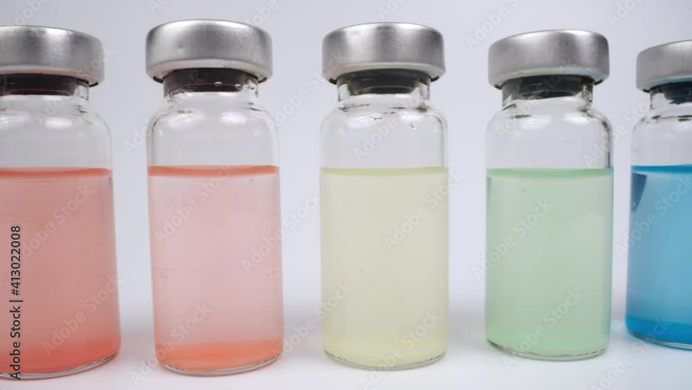 Glass vials of with different coloured liquids against white background Glass vials of with different coloured liquids against white background