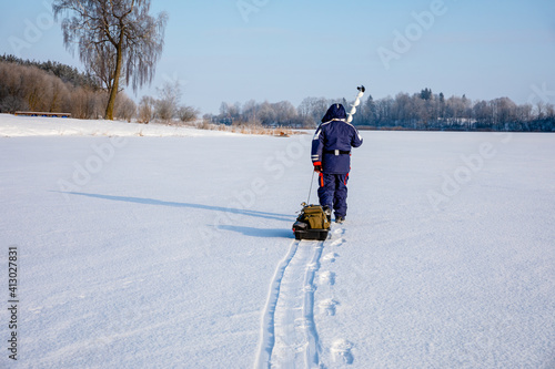 The fisherman goes to the place of ice fishing. Ice fishing concert. photo