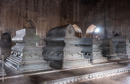 Vijayapura, Karnataka, India - November 8, 2013: Ibrahim Rauza Mausoleum. Closeup of row of several gray stone tombs in semi-dark room with only natural light. photo