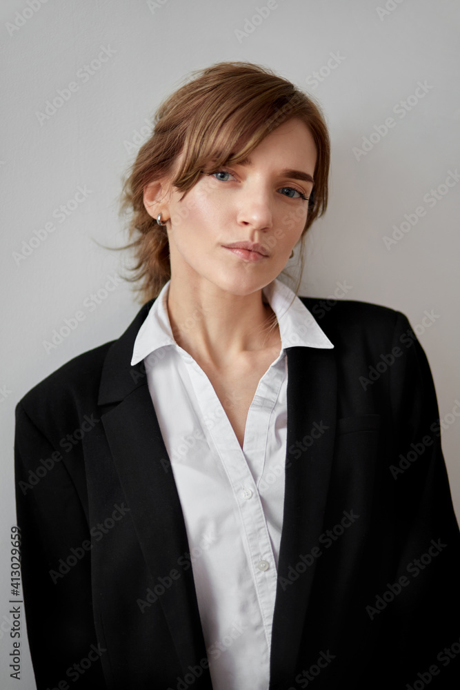 Portrait of a serious young business woman in a black jacket. He looks at the camera. Photo in the studio. Portrait of a serious young business woman in a black jacket. He looks at the camera. Photo in the studio.