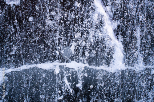Close up and abstract photo of frozen water with cracks and water bubbles in the ice.