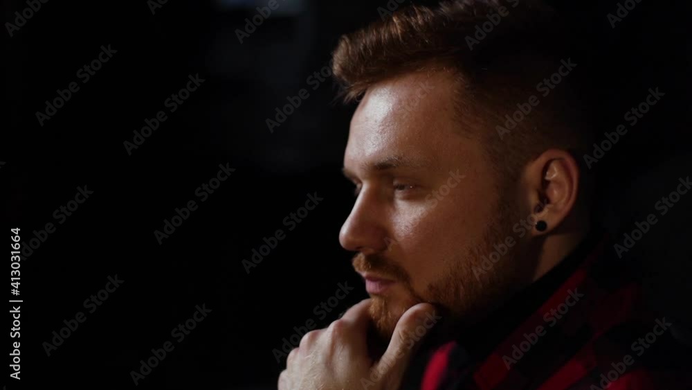 Close-up face of confident handsome business man thoughtfully holds hand near chin and looking away. Side view of successful thinking beared male at indoor with dark interior. Shooting in slow motion. Close-up face of confident handsome business man thoughtfully holds hand near chin and looking away. Side view of successful thinking beared male at indoor with dark interior. Shooting in slow motion.