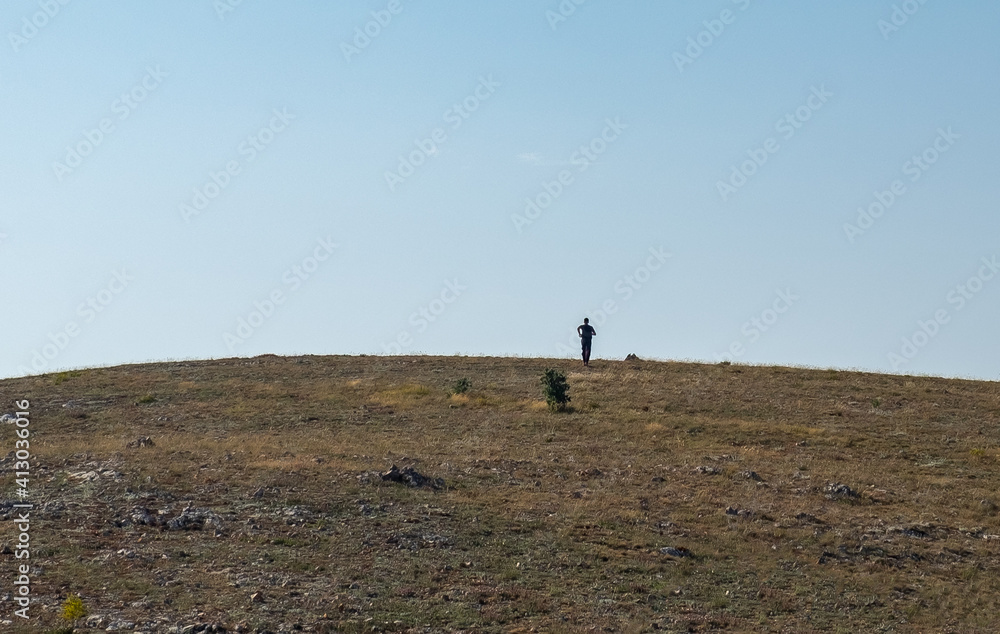 Silhouette of a young man running to the top of a high hill on a clear sunny day. Silhouette of a young man running to the top of a high hill on a clear sunny day.