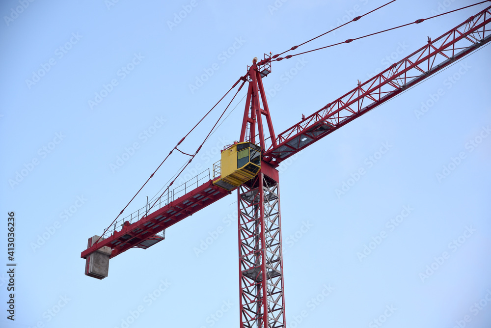 Construction crane with yellow booth on sky background