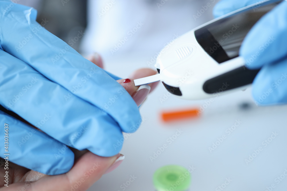 Doctor in glove makes blood sugar test on patient with glucometer Doctor in glove makes blood sugar test on patient with glucometer