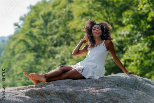 Model on top of boulder in nature photo