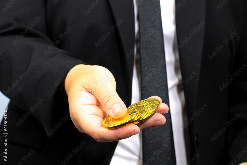 Fototapeta premium Person in black suit holding bitcoins
