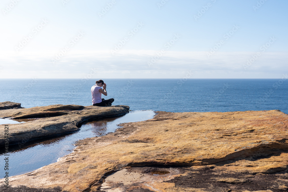 Young Woman lady Practicing Yoga on a cliff overlooking the ocean at Sunrise, Healthy Lifestyle
