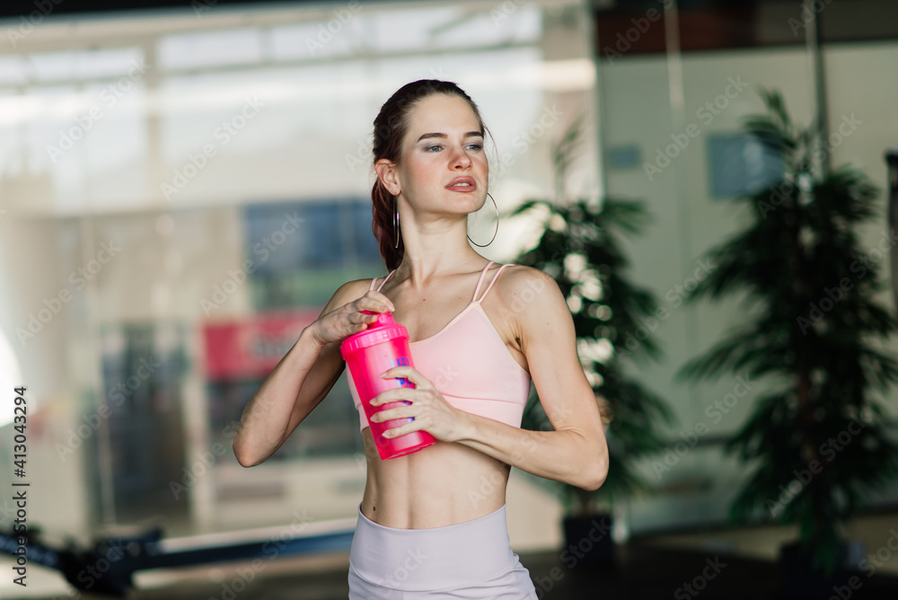 Young female at the gym trainer holding a bottle of water