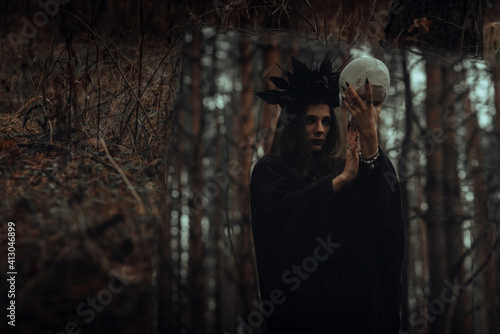 reflection in the mirror of an evil scary witch with a dead man's skull performing mystical occult rituals © alexkoral
