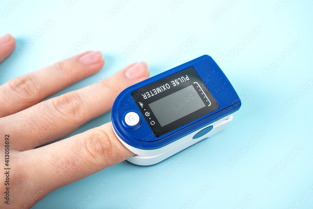 Pulse oximeter to measure pulse rate and oxygen levels isolated on blue background. Medical concept. Diagnosing coronavirus. Pulse oximeter to measure pulse rate and oxygen levels isolated on blue background. Medical concept. Diagnosing coronavirus.