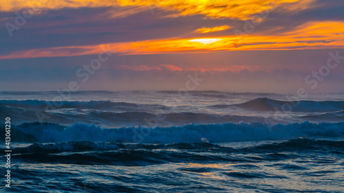 Sea landscape on sunset or sunrise with ocean waves and orange colorful clouds in sky. Concept of vacation on beach, free time, travel, summer, disconnecting from routine and relaxing.