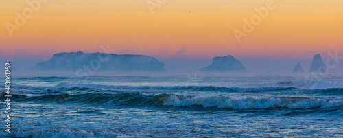 Sea landscape with ocean waves and small islands in background in a foggy environment with warm light of sunrise. Medes Islands, Mediterranean sea, Torroella de Montgri, Ampurdán-Empordà, Catalonia. photo