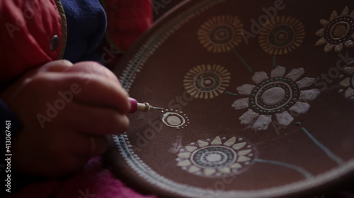Artist making decoration on clay plate in studio. Woman making ornamental decor 