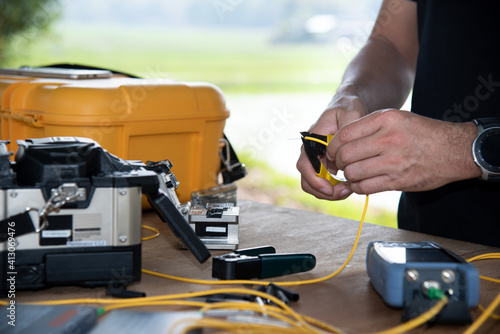 master's hands with optical fiber stripper