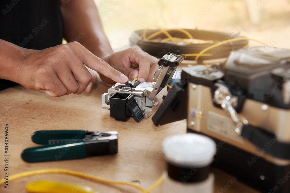 master's hands with optical fiber stripper