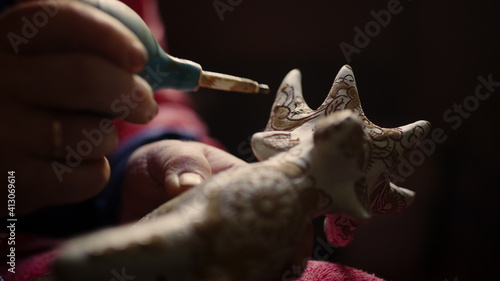 Closeup woman hands decorating product in pottery. Ceramist painting toy deer