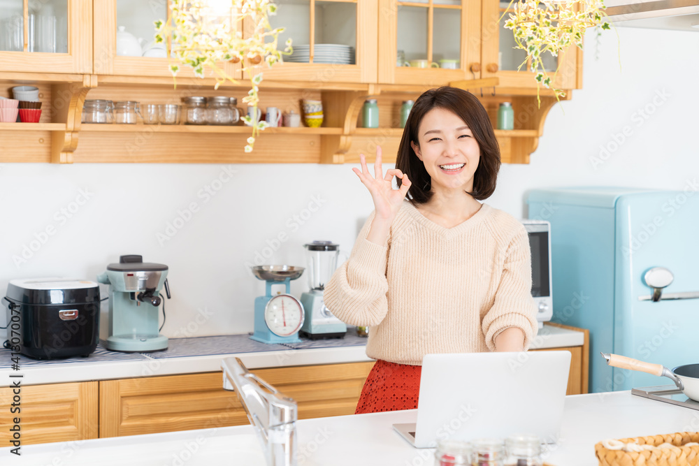 キッチンでラップトップコンピューターを見る女性 キッチンでラップトップコンピューターを見る女性