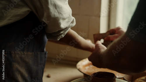 Unrecognized woman washing hands in pottery. Man cleaning woman hands in studio