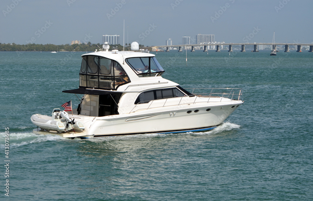 White motor yacht cruising on Biscayne Bay near Miami Beach,Florida with  causeway bridge linking Miami to Miami Beach in the background.