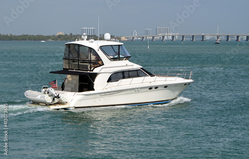 White motor yacht cruising on Biscayne Bay near Miami Beach,Florida with causeway bridge linking Miami to Miami Beach in the background.