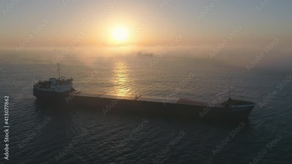 Spectacular foggy ocean sunrise and sailing cargo ship in open waters, 4K aerial drone video Spectacular foggy ocean sunrise and sailing cargo ship in open waters, 4K aerial drone video