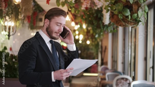 Side view of a smliling businessman talking on a phone being at cafe. Coffee break time. photo