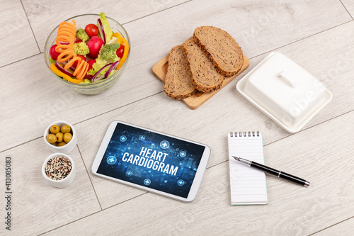 HEART CARDIOGRAM concept in tablet pc with healthy food around, top view